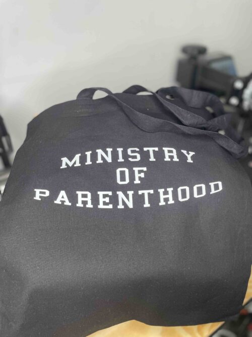 Black cotton tote bag with white text saying Ministry of Parenthood